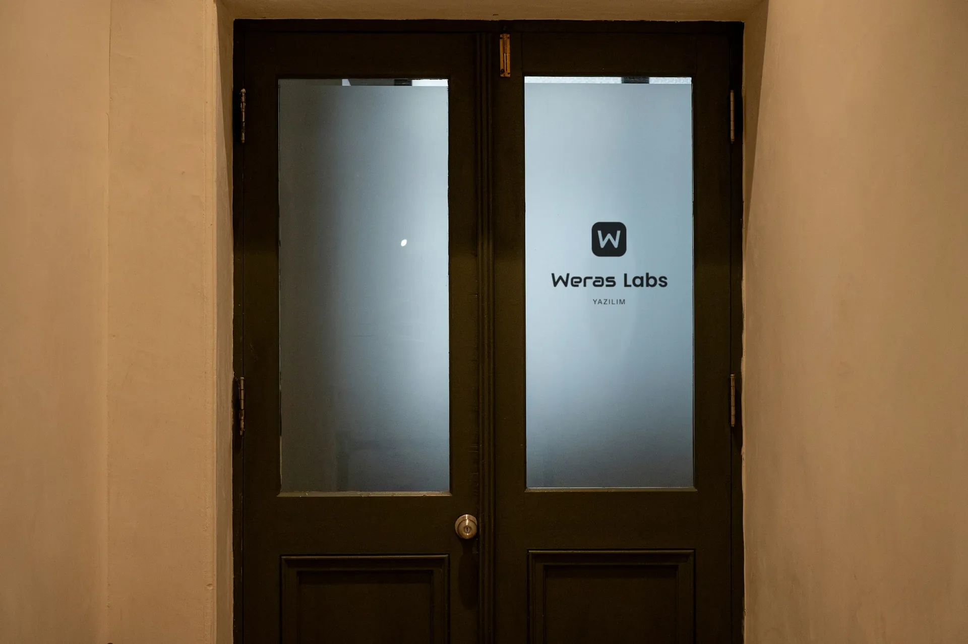 Ofis kapısının buzlu camında Weras Labs logosu
